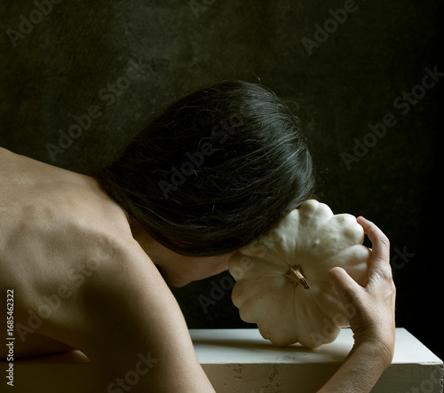 woman leaning on a white wooden board stroking a white pumpkin II
