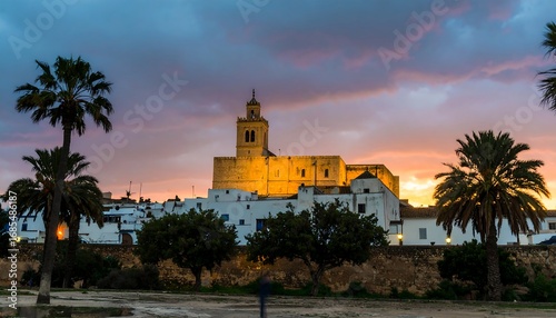 Sunset over a whitewashed town with a church and palm trees