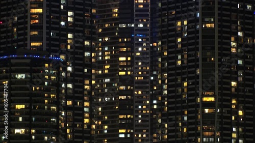 TOKYO, JAPAN - AUG 2025 : Time lapse shot of illuminated modern high rise residential apartment building with glowing windows in urban cityscape at night. Lifestyle and real estate concept.