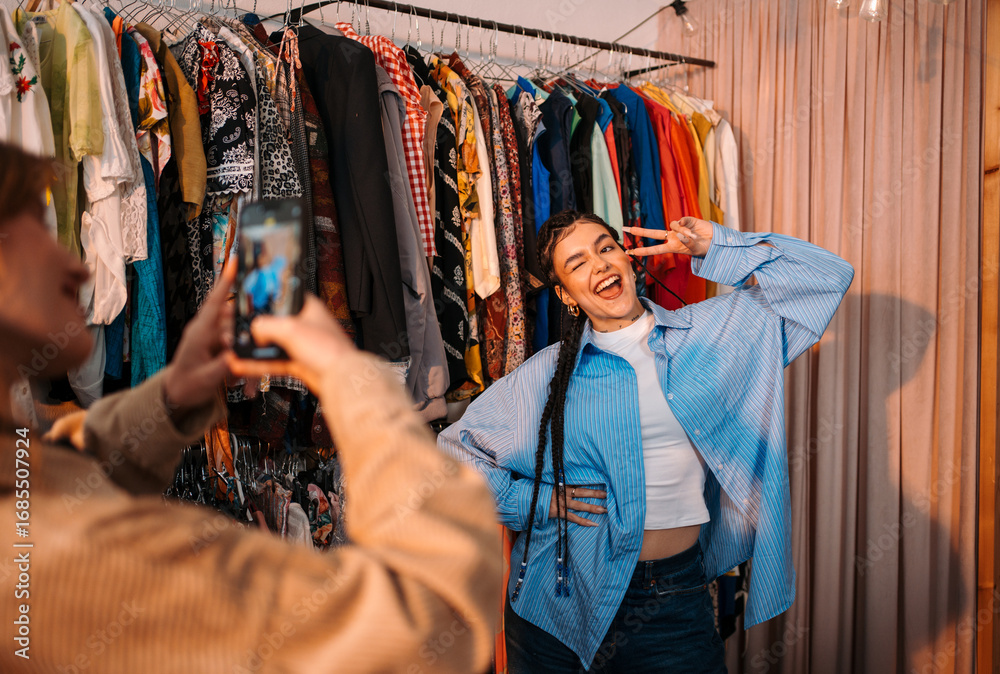 Fototapeta premium A trendy young woman confidently poses for a photo in a stylish clothing store