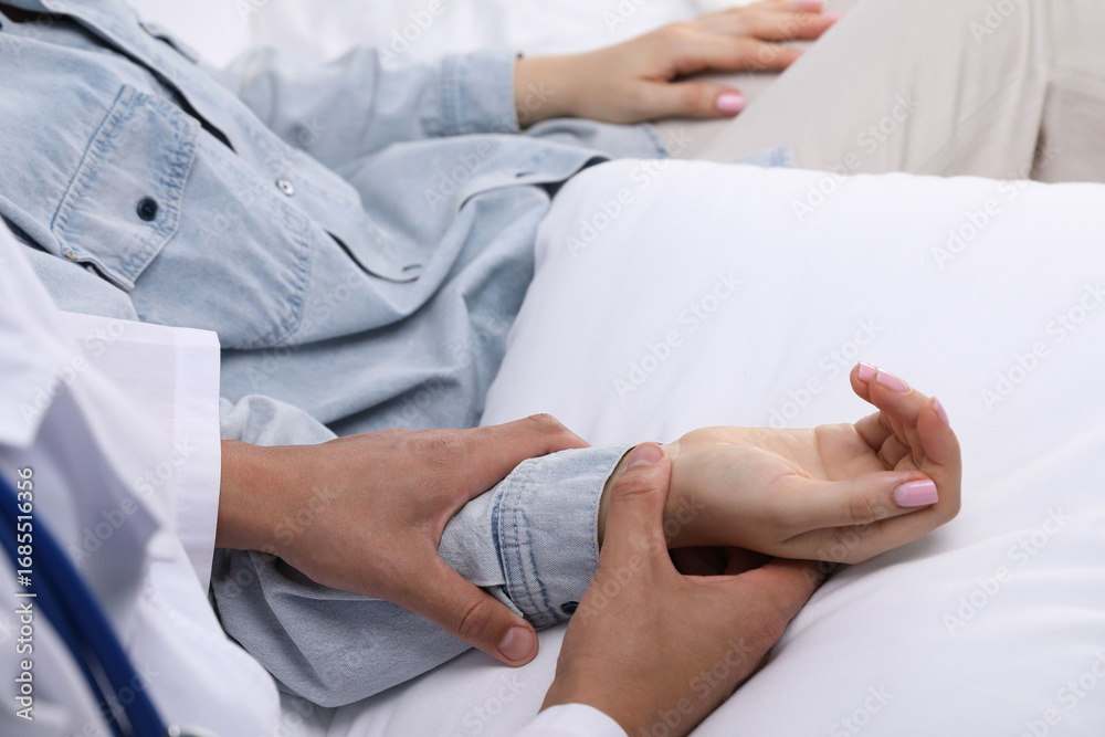 Fototapeta premium Doctor checking woman's pulse with fingers at home, closeup