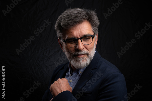 Obraz na plátne Bearded mature businessman in serious low key portrait isolated on dark studio b