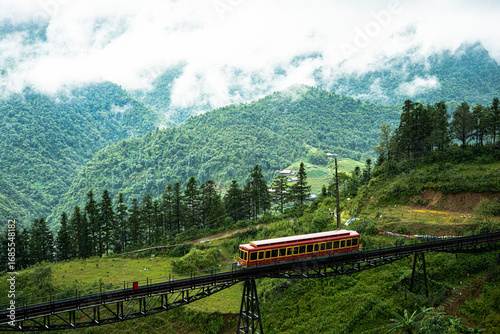 Red funicular train ascending mountain valley in Sapa, Vietnam