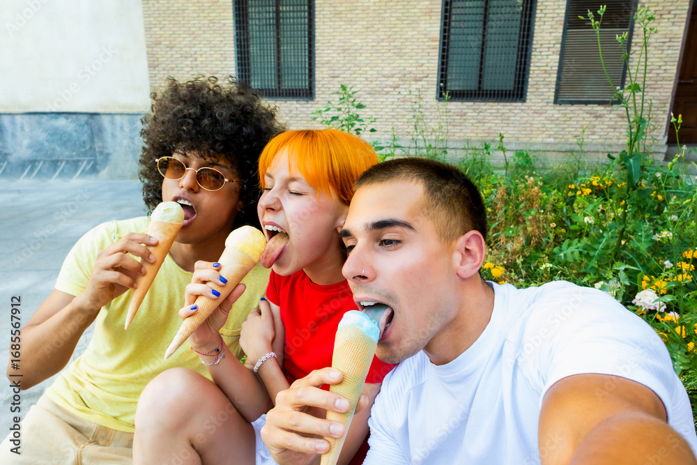 Fototapeta premium Three joyful friends enjoying ice cream cones and taking a selfie