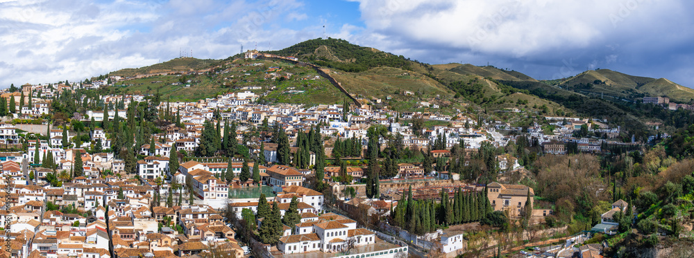Naklejka premium A panoramic view of the historic Albayzin neighborhood in Granada, Spain, with its whitewashed houses and the sprawling urban landscape.
