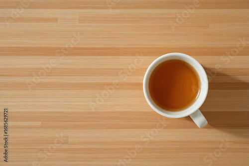 Top down view of a white ceramic mug filled with tea on a wooden surface