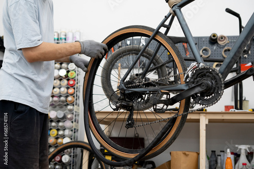 Wallpaper Mural A person is repairing a bicycle by changing a flat tire, working diligently in a well-equipped workshop Torontodigital.ca