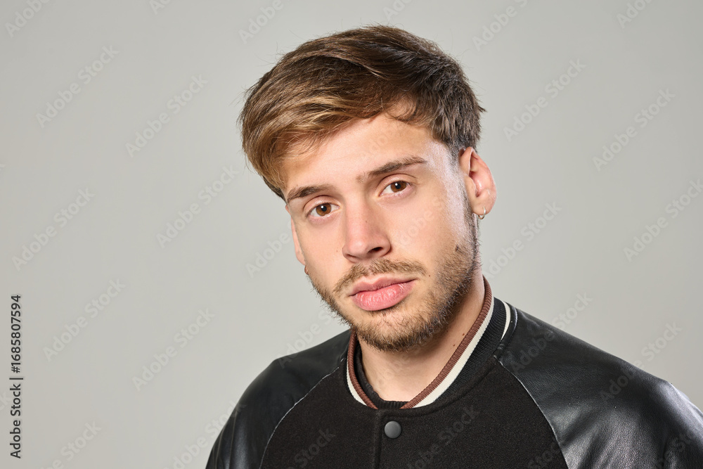 Fototapeta premium Close-up portrait of young Caucasian man with piercing looking serious in studio