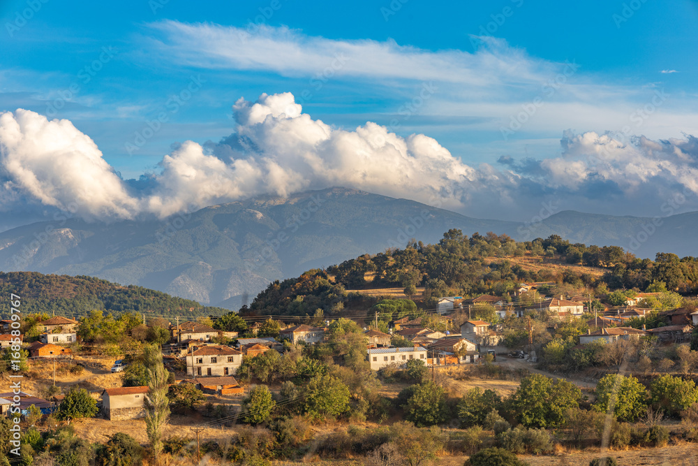 Fototapeta premium Traditional Turkish village houses on hillside with Kazdağları mountains and dramatic clouds