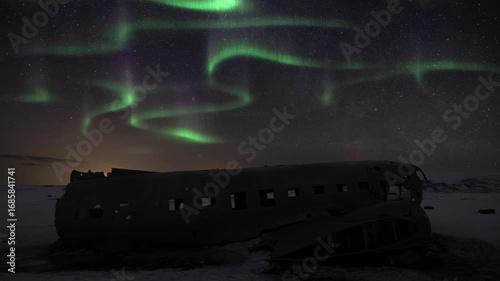 Time lapse of Aurora borealis above a crashed DC-3 Plane in Solheimasandur Iceland during winter. Tourism landmark at night with stars and sky.