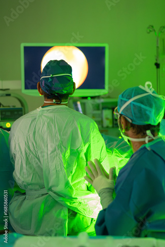 Surgeons performing laser endoscopic surgery with green light in operating room