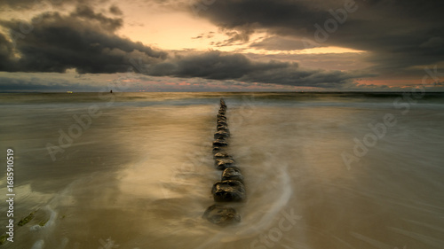 Fototapeta Naklejka Na Ścianę i Meble -  Stunning sunset over the Baltic Sea, capturing the warm golden hues reflecting on calm water. Serene coastal landscape with peaceful waves and a colorful sky.