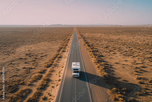 Camper van traveling on a desert road at sunset