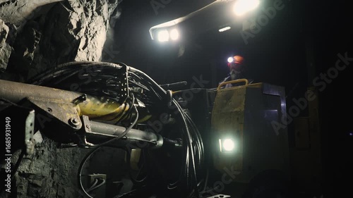 A driller works in a mine behind a drilling rig