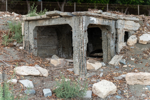 Abandoned concrete structure on the street in Limassol, Cyprus. Old shelter among stones and dry grass.
