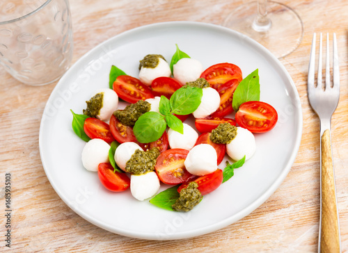 Foto Caprese salad with basil and pesto sauce served on plate
