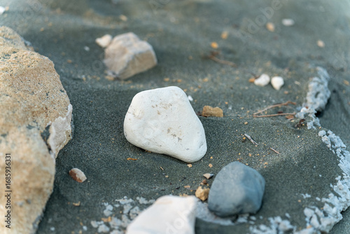 Stones of different colors on a sandy beach, close-up, natural texture.
