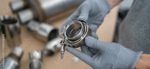Foto Mechanic holds a v-band exhaust component with focus on details, while preparing for assembly in an automotive repair workshop setting