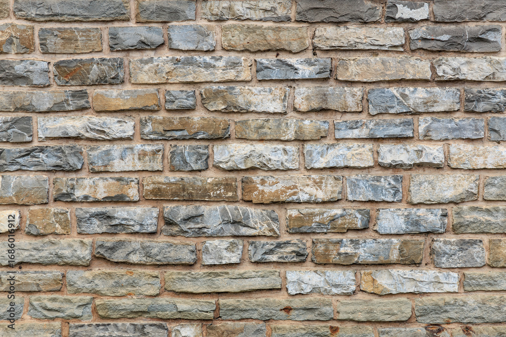 Fototapeta premium Textured gray and beige brick wall with rough stonework pattern