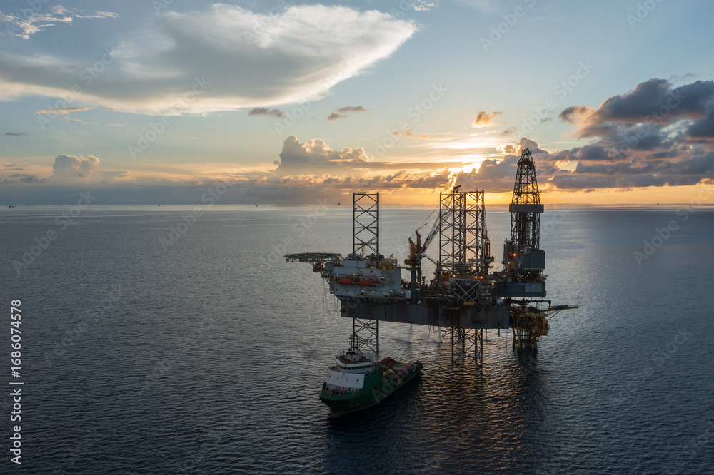Fototapeta premium Aerial view of offshore jack up rig and offshore platform during sunset for oil and gas exploration and production.