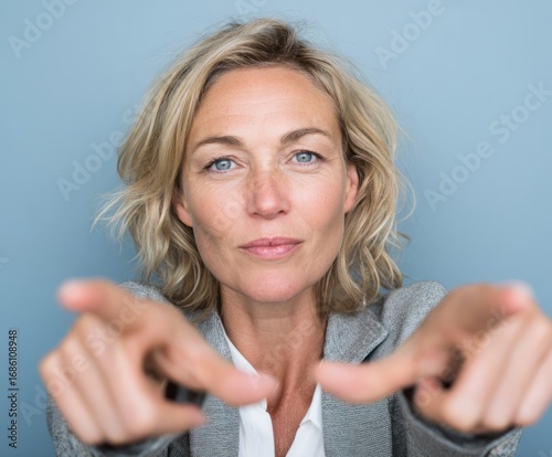 A mature woman with direct, assertive body language directs attention toward the viewer.