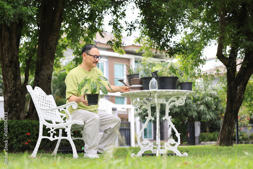 Asian senior man relaxing with gardening potted plants in front yard