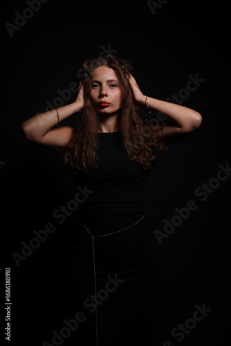 Low key portrait of pretty brunette woman in black dress