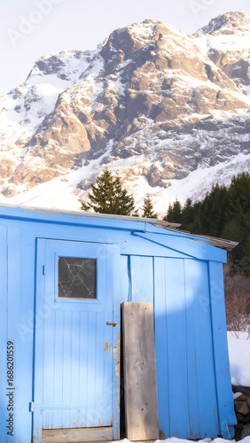 Blue shed against snowy mountain