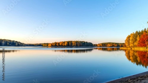 Serene autumn landscape reflection on tranquil lake with colorful trees at sunset horizon