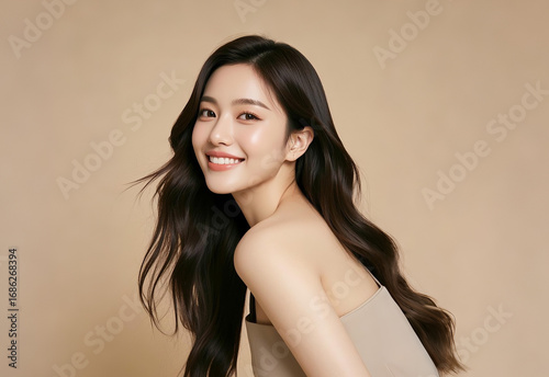 Girl in a beige knit short-sleeved top, with sleek wavy hair, flashing a confident smile against a warm-toned backdrop