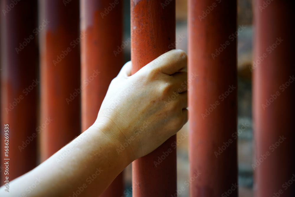 Obraz premium Close-up of Hand Grasping Red Metal Bars in an Industrial Setting