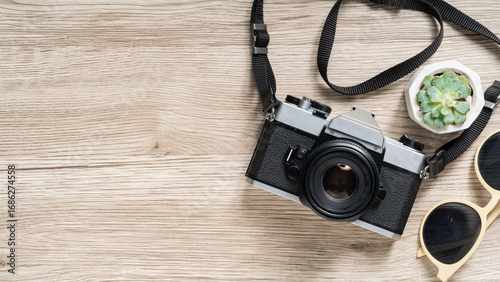 Stylish vintage camera and trendy sunglasses on a wooden surface create a cool travel vibe