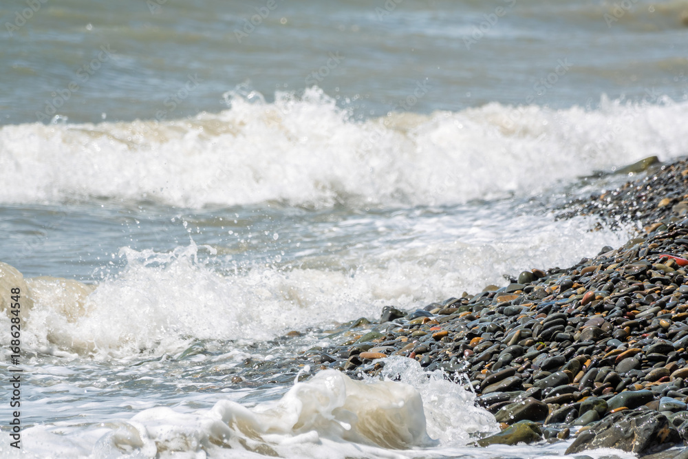 Fototapeta premium Sea water splashing over the stones on the beach