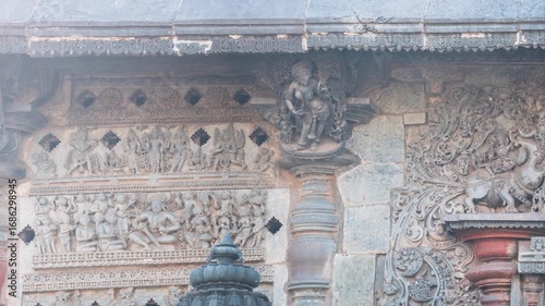 Pan: Detailed stone carving Halebeedu ancient temple Karnataka India showing warriors deities animals intricate sculptural art symbolizing heritage culture devotion