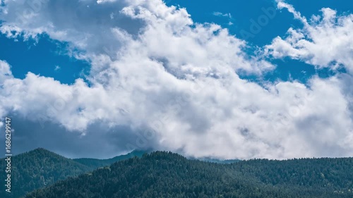 Time lapse: Alps Italy mountain forest ridge under vast sky with dramatic cumulus clouds, capturing grandeur of nature, scale of wilderness, essence of freedom and awe
