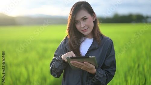 A young woman smiles gently against a backdrop of lush green fields, embodying tranquility and natural beauty in a serene outdoor setting.