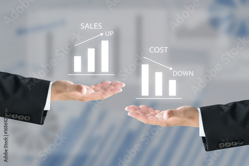 セールスアップとコストダウンの棒グラフを掲げるビジネスチーム