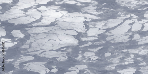 Aerial view of ice floes drifting across a gray water surface illustrating climate change
