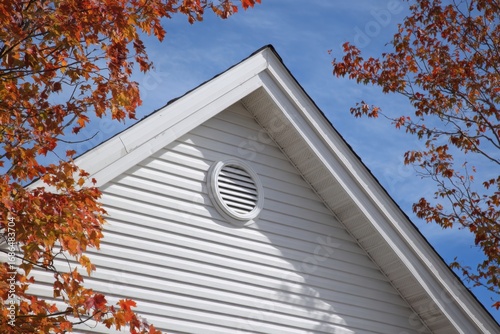 Gable roof circular vent allowing air circulation on clear day. Ventilation of the house. Fascia and Ridge. Grey metal tiles roof. Siding house exterior. Outdoor air conditioning. Architectural Detail