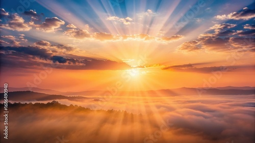 Majestic sunrise illuminates the sky with golden rays breaking through clouds over misty mountains