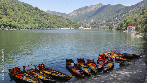 Scenic shot of Naini Lake featuring wooden boats, located in Nainital, Uttarakhand, India.