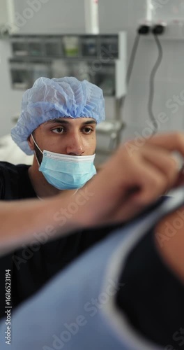 A surgeon in a surgical mask and cap prepares for surgery. The image shows a medical professional putting on his gloves. Surgeon Preparing for Surgery