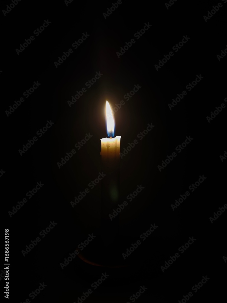 Fototapeta premium Candle light at night. Burning candle in darkness with focus. White candle burning in the dark, candle flame burning in the dark. Light a candle when the lights go out, relaxation and tranquility.