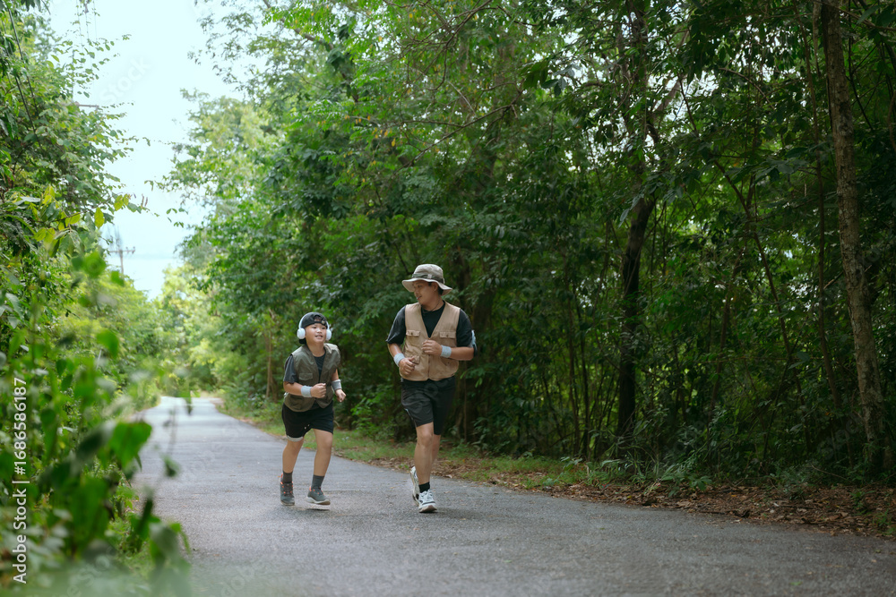 Fototapeta premium Father and son enjoy quality time together while jogging on a forest trail during a sunny afternoon