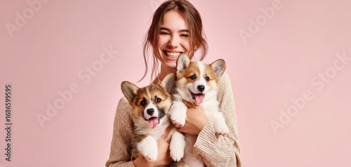 The Corgi Puppies Held by a Smiling Woman in a Pink Studio Portrait