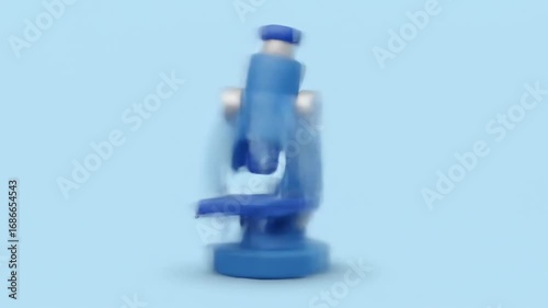 A cartoon-style, blue microscope stands against a light-blue background. It has a rounded base, a central cylindrical body, and eyepieces
