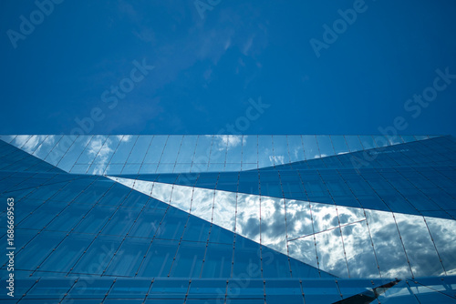 Glass facade with blue tones and light reflection, abstract architectural minimalism symbolizing design, geometry, transparency, urban identity and contemporary background