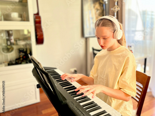 Teen learning piano with tablet sheet music and headphones, symbolizing modern technology, digital apps, and innovative ways of studying music at home.	