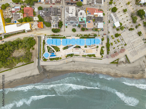 Aerial view of a coastal building displaying turquoise pools contrasting sharply with the beige beach and the deep blue ocean, Puerto Colombia, Atlantico, Colombia.