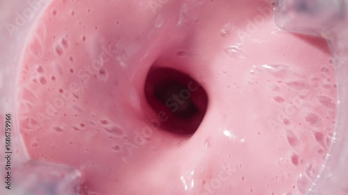 Strawberry and banana pink milkshake blended in blender with splashes. top view. slow motion. Healthy protein smoothie drink concept , food closeup. Protein powder falling in smoothie from spoon